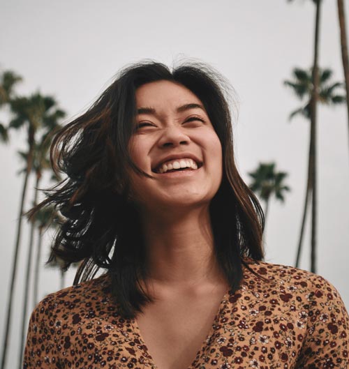 Photo of girl laughing in front of palm trees