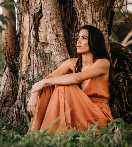 Image of a woman sitting by a tree